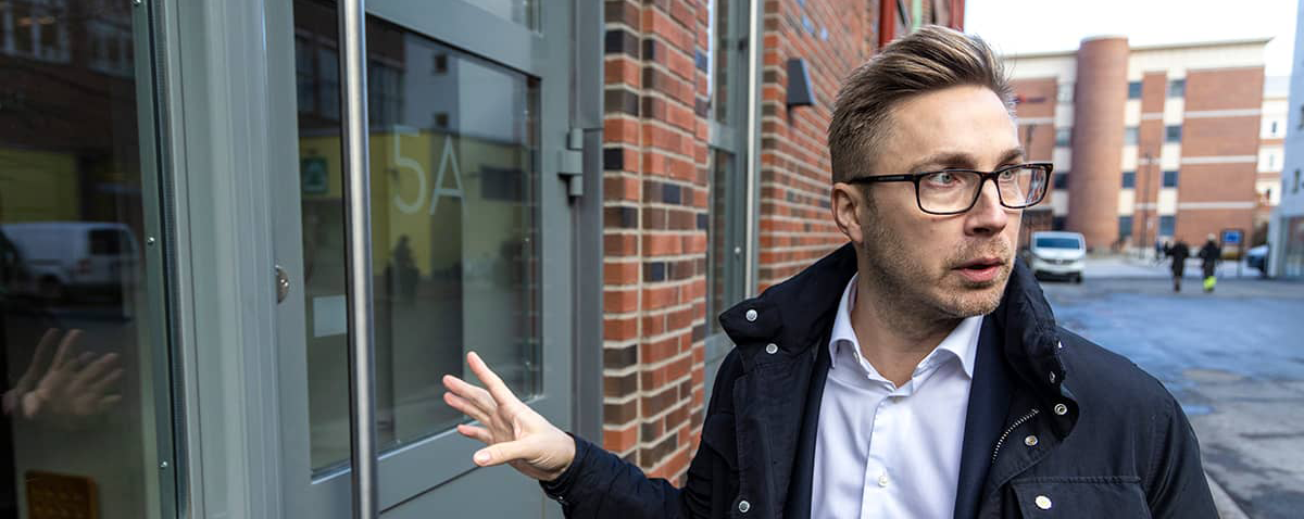 Ordförande i BRF Fabriksparken står utanför en entrédörr till fastigheten