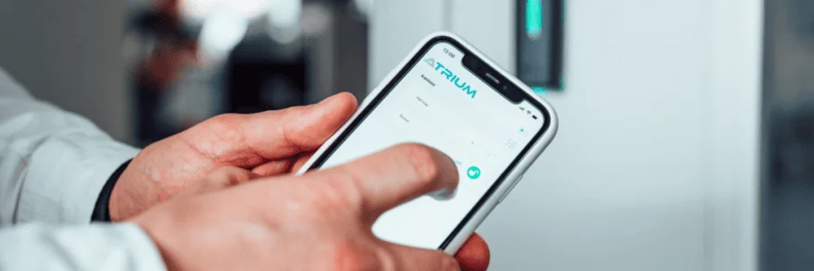 Man håller i mobilen som vidar ATRIUM. I bakgrunden ser man en läsare